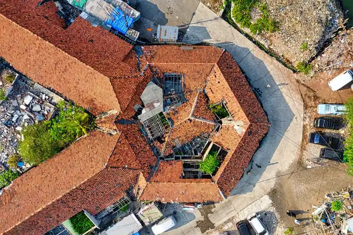 Aerial drone shot capturing a rooftop in Jakarta, showcasing unique architectural design with fallen debris around.