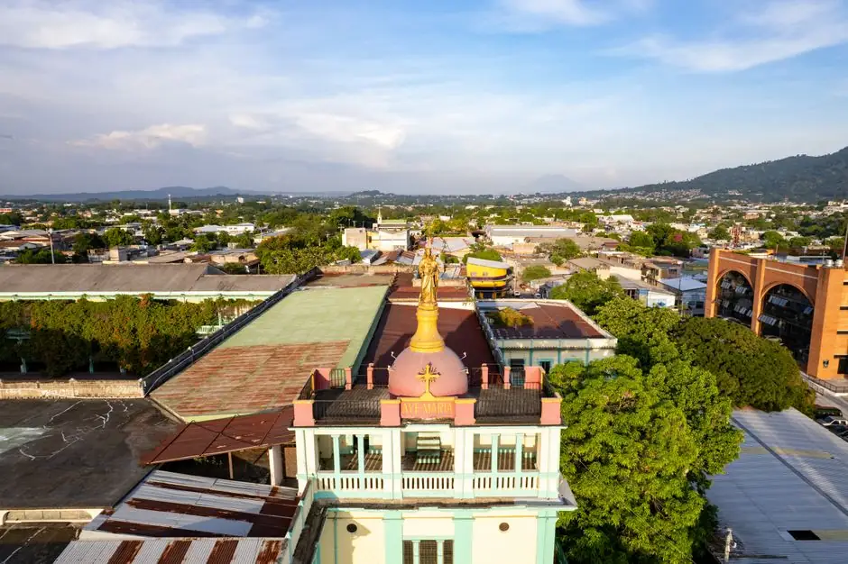 Aerial view of a church and cityscape in San Salvador, El Salvador, under a sunny sky.